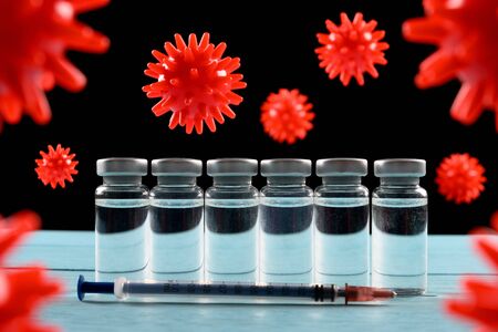vaccine and syringe surrounded by coronavirusの写真素材