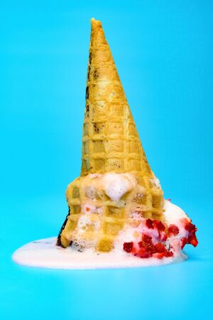 vanilla and strawberry flavor ice cream cone melted on blue background