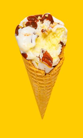 angle view fresh vanilla flaovr ice cream cone with chocolate with couple of bites on a yellow...