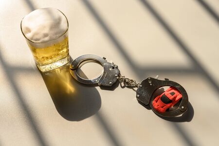 car and handcuffs and cup of beer in jail concept of illegal drunk driving