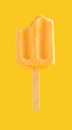 half eaten mango pudding flavor ice cream stick on a yellow backgroundの写真素材