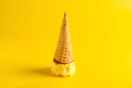 vanilla flavor ice cream cone melting on blue backgroundの写真素材