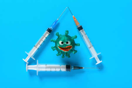 top view coronavirus surrounded by triangle shape syringes on blue background horizontal compositionの写真素材