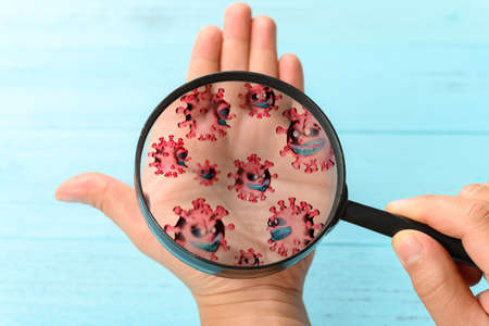 looking at the hand with a magnifier and seeing lots of coronavirusの写真素材