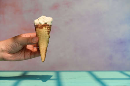 hand holding a half eaten toffee flavor ice cream cone in a sunny morning
