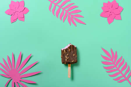 top view a bitten chocolate ice cream  with paper cutting flowers and leaves on green background