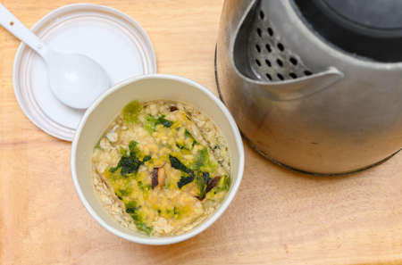 preparing pork and mushroom flavor instant  porridge with kettle nearbyの写真素材