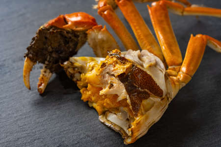 half of a cooked crab with lots of  crab roe on a dark background