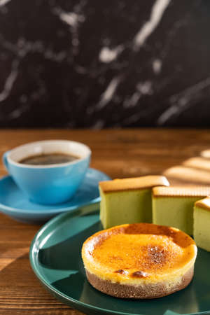 cheese cake with matcha cakes and cup of coffee at background in a sunny morning vertical compositionの写真素材