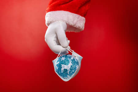 Santa Claus holding a medical mask with a blue Christmas ball on redの写真素材