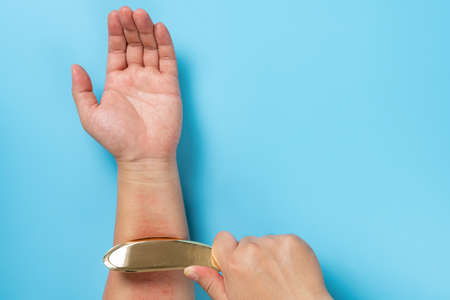 man scraping his arm by a copper scratcher which is a traditional Chinese medical treatment