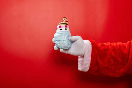 Santa Claus holding a snowman model wrapped by amedical mask on redの写真素材