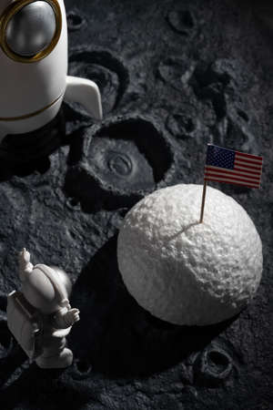 astronaut cheering up and facing the American flag on a planet with craters at vertical compositionの写真素材