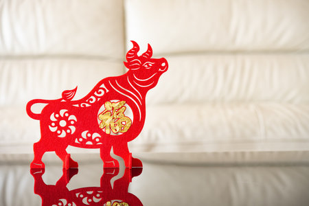an ox mascot as symbol of Chinese New Year of the Ox in front of a sofa the Chinese means good luckの写真素材