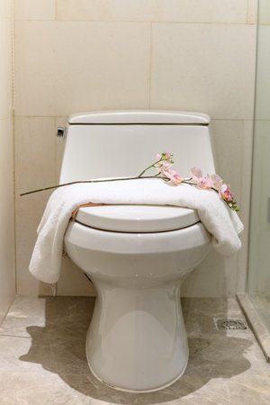 closestool with a white towel and artificial flower on topの写真素材