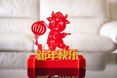 ox mascot with a lantern in front of a sofa as symbol of Chinese New Year of the Ox 2021 the Chinese means happy Chinese new yearの写真素材