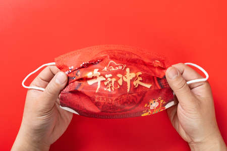 man holding a medical mask printed with Chinese characters means bullish year of Oxの写真素材
