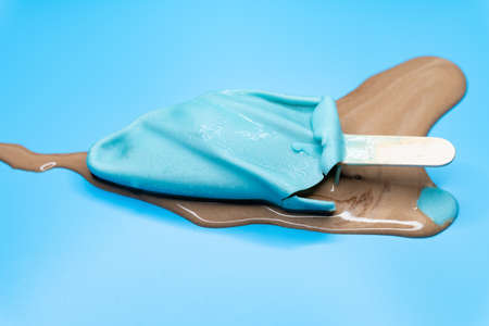 side view half melted chocolate outer with coffee inside ice cream stick on a blue backgroundの写真素材