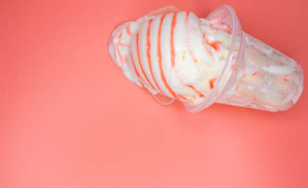 top view vanilla ice cream cup in a melting process on a pink background