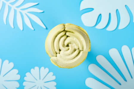 flower shape matcha flavor ice cream cone on a blue background with flowers and leaves paper cuttingsの写真素材