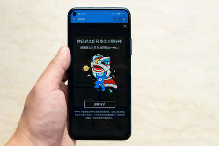 Zhongshan,China-July 1,2021:Chinese man holding a mobile showing two shots COVID-19 Vaccination have been done.The Chinsee means you have vaccinated two shots and thanks for your cooperation.のeditorial素材