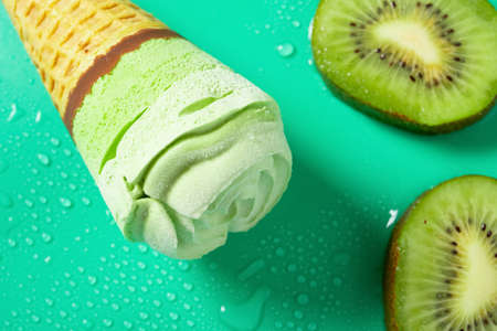 top view fresh kiwi fruit slices and a kiwi fruit flavor ice cream cone on green background