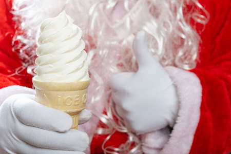 santa claus one hand holds an ice cream cone and the other hand with thumbs upの写真素材