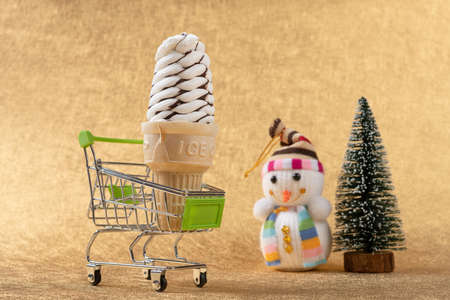 ice cream cone in a shopping cart with Christmas tree and snowman nearbyの写真素材