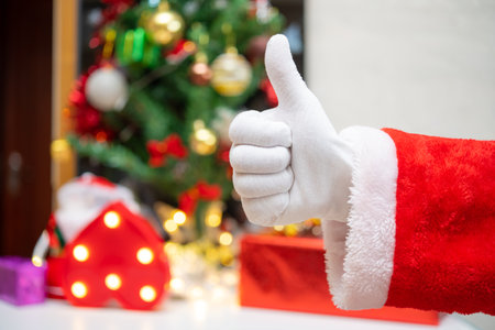 Santa Claus doing a thumbs up gesture with decorated Christmas tree on backgroundの写真素材