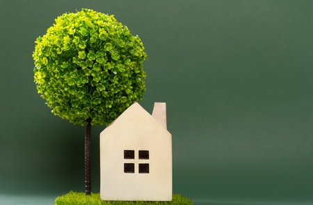 a house model on green grass with a tree on backの写真素材