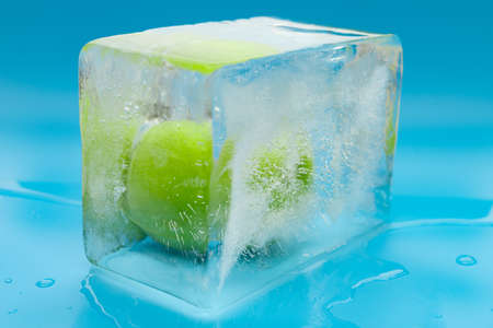 frozen green apple on a blue backgroundの写真素材