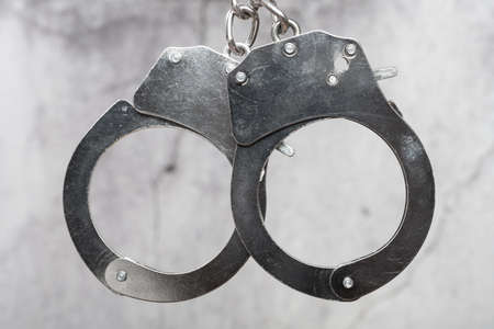 pair of handcuffs in front of a cement wallの写真素材