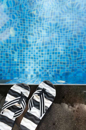 top view swimming pool and pair of slippers vertical compositionの写真素材