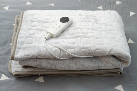 folded electric blanket with controller on the bed at horizontal compositionの写真素材