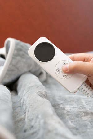 man operating a controller of an electric blanket vertical compositionの写真素材