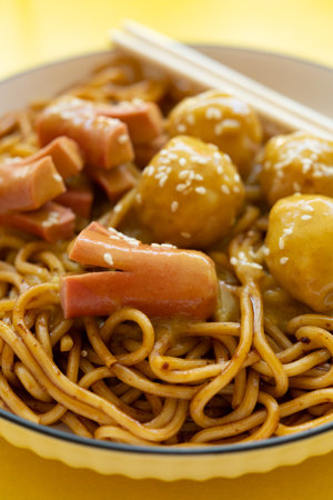 dish of cart noodles with curry fish balls and sausages close up vertical composition