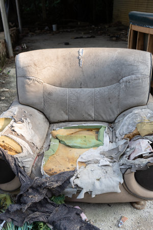 a badly damaged sofa in the outdoor at vertical compositionの写真素材