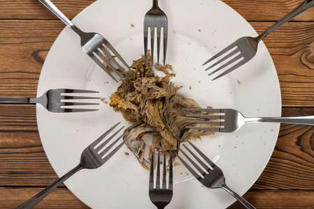 last bit of moldy vegetable surrounded by forks concept of lack of foodの写真素材