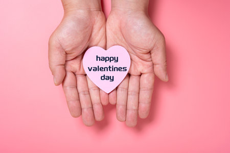 man holding a heart shape paper written with happy valentines day