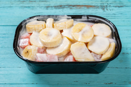 angle view fresh banana slices and watermelon blocks with yogurt at horizontal compositionの写真素材