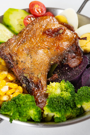 angle view healthy meal with roasted chicken leg and cucumber and eggs and broccoli and sweet potatoes and maize and cherry tomatoes at vertical compositionの写真素材