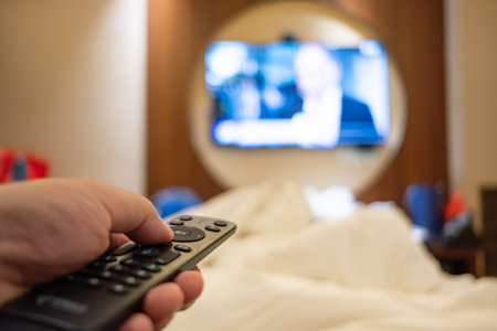 man operating a TV remote control in a hotel roomの写真素材