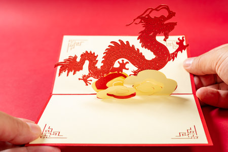 hands holding a pop-up greeting card with a dragon