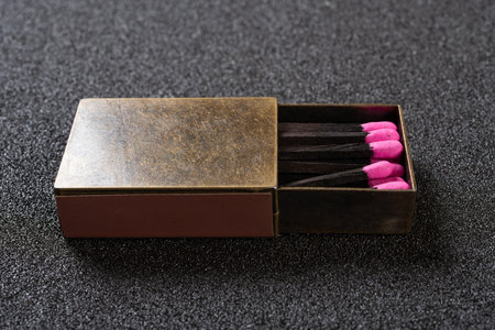 angle view copper matchbox with pink color match sticks at horizontal composition