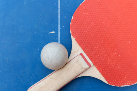 top view table tennis racket and ball and net on a blue table tennis table at horizontal compositionの写真素材