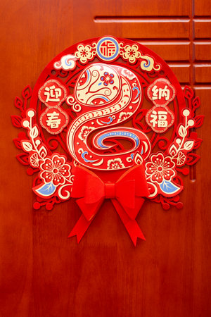 a Chinese New Year of the Snake decoration to a door at vertical composition translation of the Chinese characters are Welcoming Spring and Embracing Fortune no logo no trademarkの写真素材