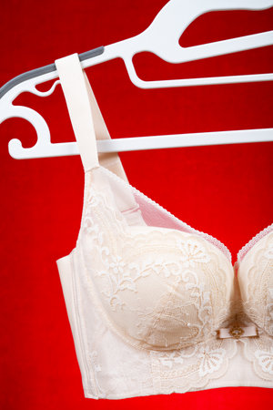 beige bra hanging on red background at vertical compositionの写真素材
