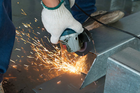 skilled worker cutting an iron pipe with a grinderの写真素材