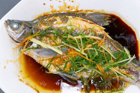 fresh steamed whole fish with ginger and sauceの写真素材