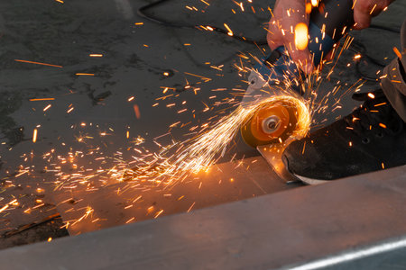 skilled worker cutting an iron pipe with a grinderの写真素材